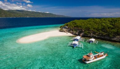 フィリピンの離島に広がる白い砂浜とエメラルドグリーンの海、浮かぶバンカーボート