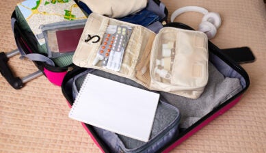 スーツケースに常備薬を収納した整理ポーチや地図、パスポートを準備する海外旅行の薬の持ち込み準備の様子