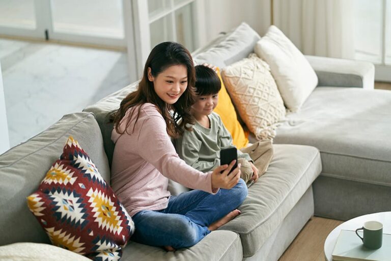 ソファで子どもと一緒にスマホを見ながら台湾の子連れ旅行を計画する母親