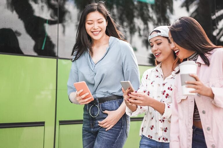 台湾の街中でスマホの地図アプリを見ながら笑顔で移動する女性3人組