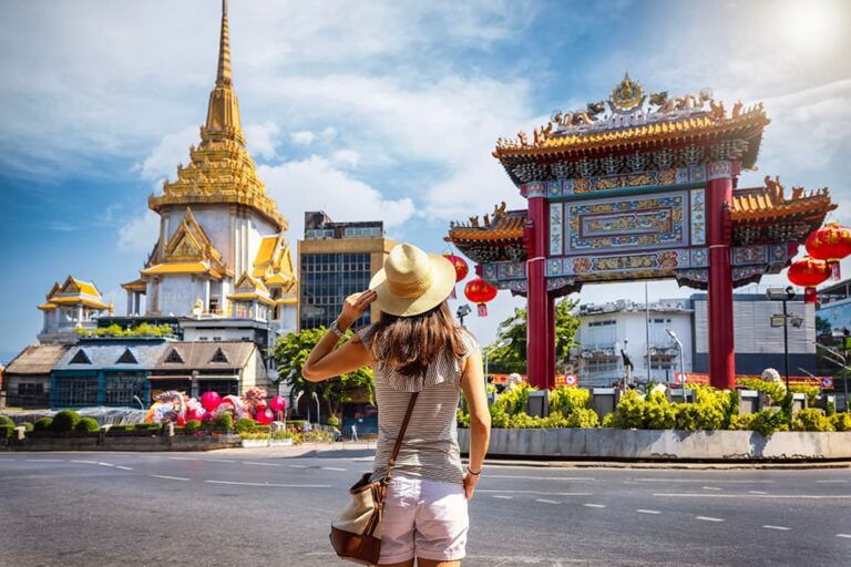 晴天のバンコクで、黄金の寺院や中華門を眺めながらタイ観光を楽しむ女性の後ろ姿
