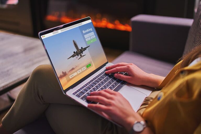 ノートパソコンで航空券予約サイトを開きカーニバル旅行の計画を立てる女性