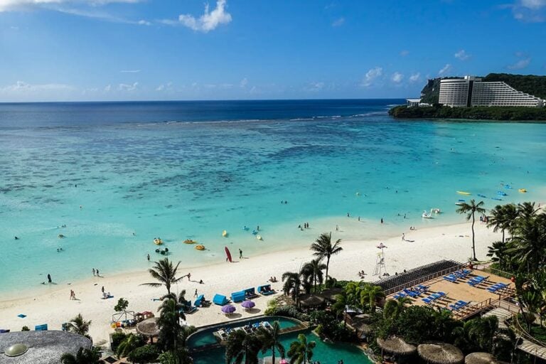 波が穏やかで遠浅な海が広がるグアムのリゾートビーチ。小さな子連れでも安心して水遊びができる安全な環境の風景