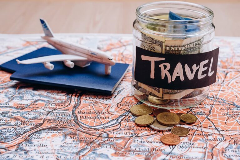 地図の上に置かれた「TRAVEL」と書かれた貯金瓶と飛行機の模型。子連れグアム旅行の3泊4日の費用めやすや、賢く予算を抑えるための節約ポイントをイメージした一枚