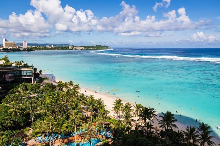 青い空とエメラルドグリーンの海が広がるグアムのタモン湾沿いのビーチ（日数や人数によって変わるグアム旅行の費用目安を解説する章のイメージ）
