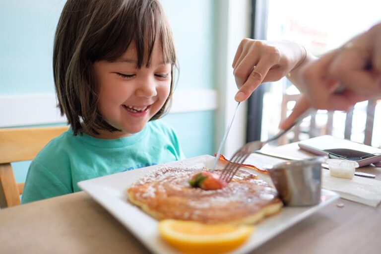 ハワイのカフェでパンケーキを前に笑顔を見せる子ども、家族で楽しむ朝食グルメの様子