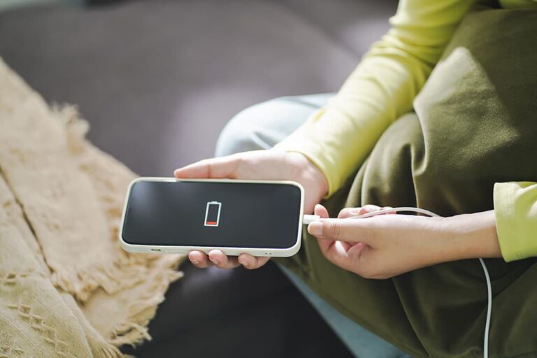 バッテリー残量が少ないスマートフォンに充電ケーブルを差し込もうとする手元