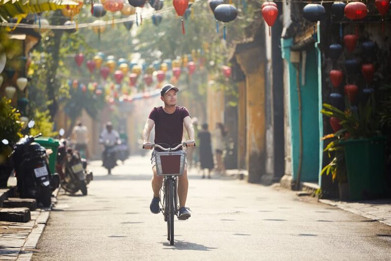 色とりどりのランタンが揺れるホイアン旧市街を、自転車で巡る男性旅行者