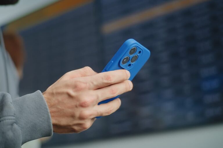空港の発着案内板の前でスマートフォンの通信設定を確認する旅行者