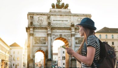 ミュンヘンの戦勝門前でスマートフォンを使うドイツ旅行者