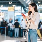 空港でスマートフォンの通信状況を確認する旅行者