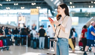 空港でスマートフォンの通信状況を確認する旅行者