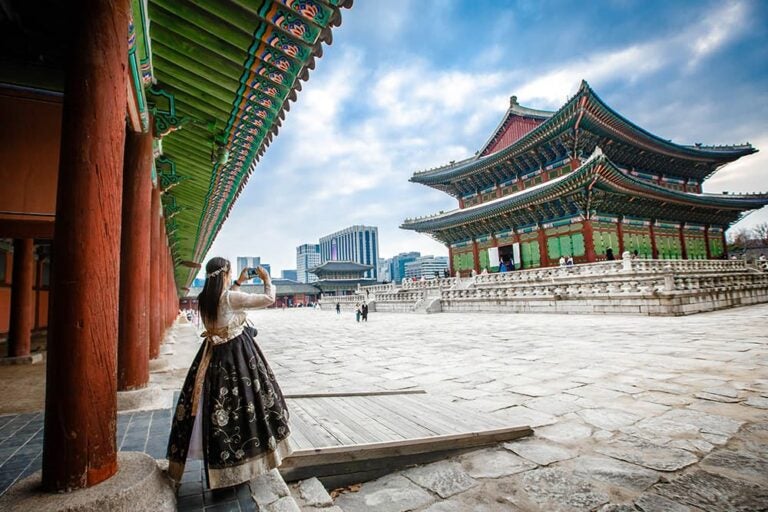 韓服姿でスマートフォンを使い景福宮を撮影する女性、韓国旅行中の通信環境が活躍する場面