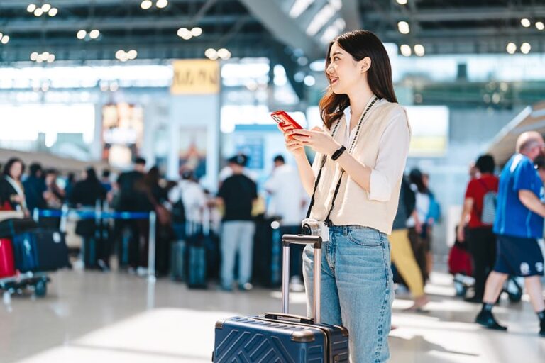 台湾の空港でスマホを使う女性旅行者、eSIMで到着後すぐ通信
