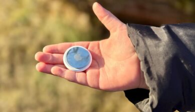 屋外で手のひらにAirTagを載せて見せている様子