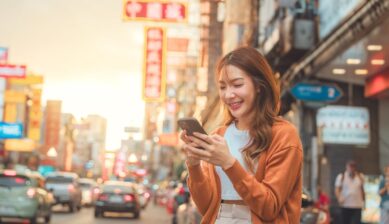中国の街中でスマートフォンを操作する女性旅行者