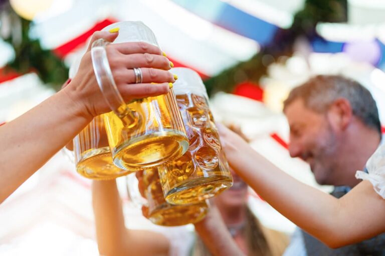 オクトーバーフェストの会場で大きなビールジョッキを掲げて乾杯する参加者たちの様子
