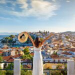 ギリシャの港町を見渡す白いドレスの女性