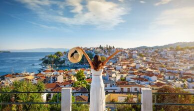 ギリシャの港町を見渡す白いドレスの女性