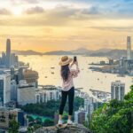 香港の高台からビクトリア・ハーバーと街並みを眺める女性旅行者