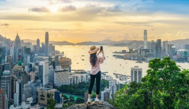 香港の高台からビクトリア・ハーバーと街並みを眺める女性旅行者