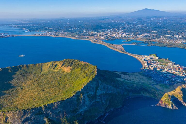 済州島の城山日出峰と周囲に広がる海や街並みを上空から望む景色