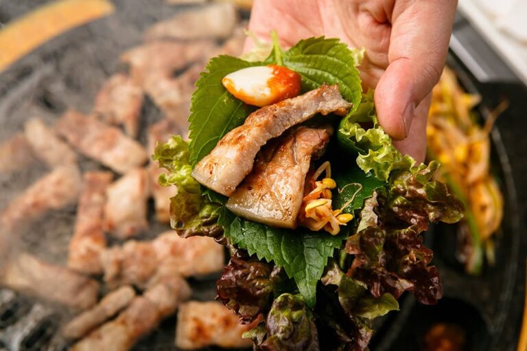 鉄板で焼いたサムギョプサルをサンチュやエゴマの葉、にんにくと一緒に包んだ韓国料理