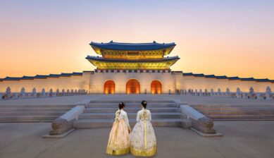 夕暮れのソウル・景福宮の光化門を韓服姿の観光客が眺める様子