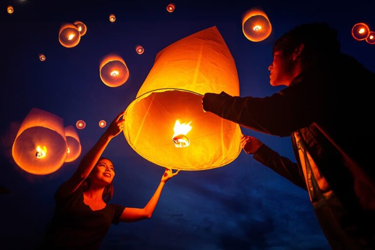 カップルが火を灯したコムローイを夜空へ放つ瞬間を撮影した写真