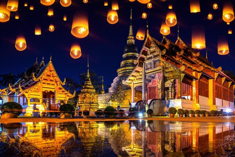 ライトアップされたチェンマイの寺院と夜空を彩るコムローイが水面に反射する光景