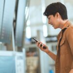 空港でスマホを確認する男性。トリファeSIMをアクティベートできない場合の対処法を示すイメージ