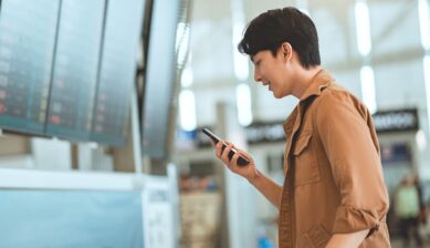 空港でスマホを確認する男性。トリファeSIMをアクティベートできない場合の対処法を示すイメージ