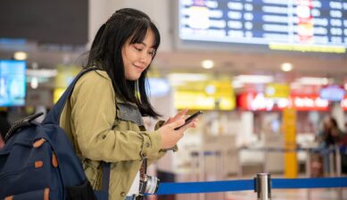 空港でスマートフォンを操作し、トリファeSIMの設定を確認する旅行者