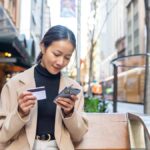 海外旅行中にスマートフォンでeSIM料金を確認する女性