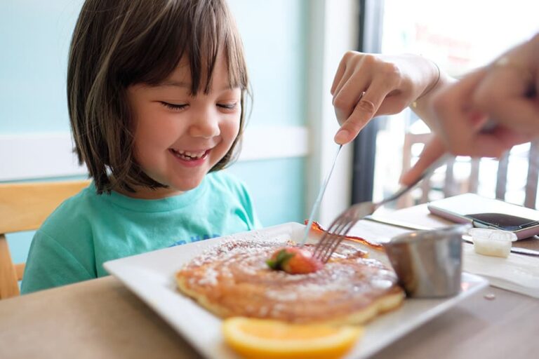 イチゴや粉砂糖を添えたアメリカ定番のパンケーキを子どもの前で切り分ける様子