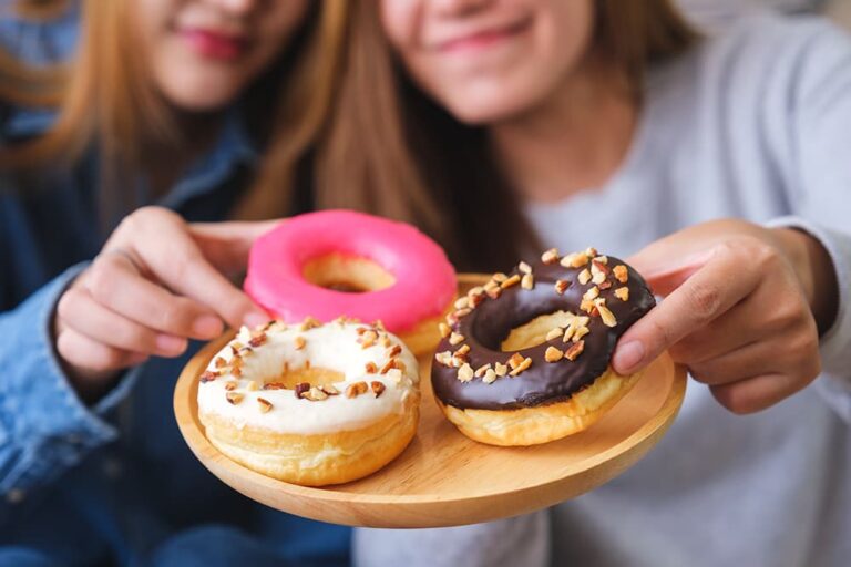 チョコレートやピンク色のアイシングで飾ったアメリカ定番のドーナツを選ぶ様子