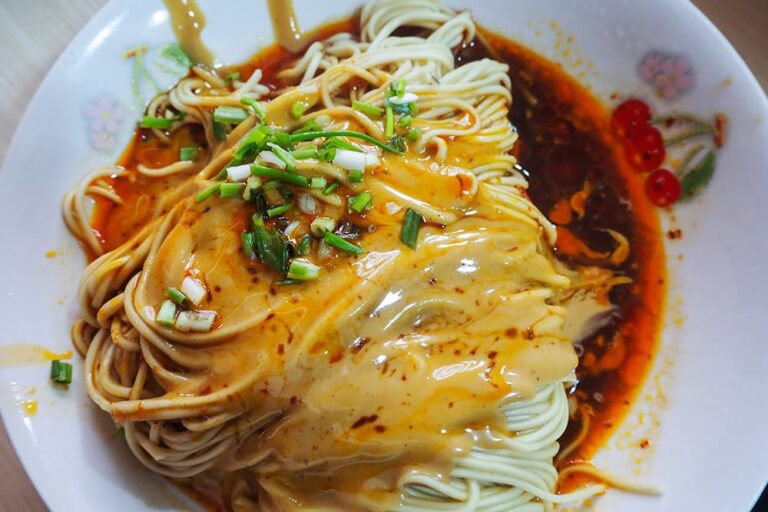 白い皿に盛り付けられた上海名物の葱油拌麺（ネギ油の和え麺）。細麺に風味豊かなタレと油、刻みネギがたっぷりと絡んでいる様子