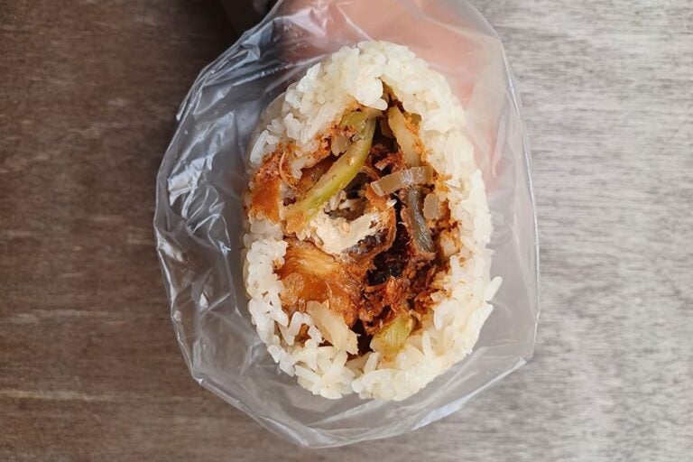透明な袋に包まれた上海の定番朝食であるもち米おにぎり「粢飯団」。断面からは揚げパンや肉松（豚肉でんぶ）などの具材がたっぷり詰まっている様子が見える