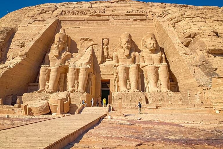 ヌビア地域（アスワン近郊）に位置するアブ・シンベル神殿の正面に佇む、4体の巨大なラムセス2世像と観光客の姿