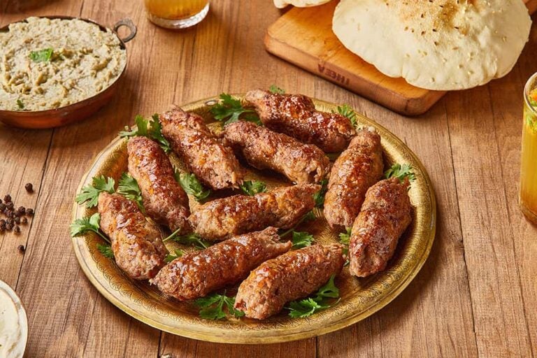 エジプトの代表的な食べ物である、ひき肉を香ばしく焼き上げた肉料理「コフタ」が金色の皿に盛られた様子