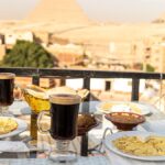 雄大なピラミッドを背景にしたテラス席で楽しむ、エジプトならではの食べ物やコーヒーが並ぶ食事風景