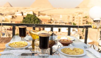 雄大なピラミッドを背景にしたテラス席で楽しむ、エジプトならではの食べ物やコーヒーが並ぶ食事風景