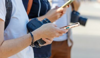 海外旅行中にiPhoneの設定画面を開き、高額請求を防ぐためにデータローミングがオフになっていることを確認し、画面上の警告ポップアップを見ている観光客の手元