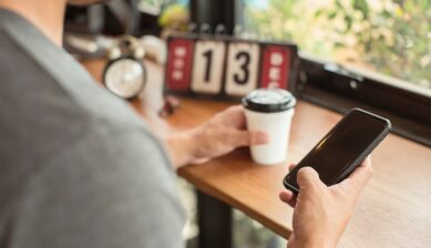 カフェでコーヒーを片手にスマートフォンを確認する旅行者