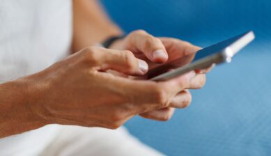 SIMフリーiPhoneの利用をイメージした、スマートフォンを操作する人の手元
