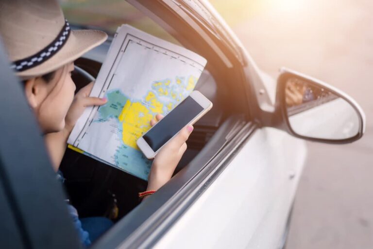 海外旅行中のギガ消費を節約するため、スマートフォンの通信を控えて紙の地図を確認している車内の旅行者の様子