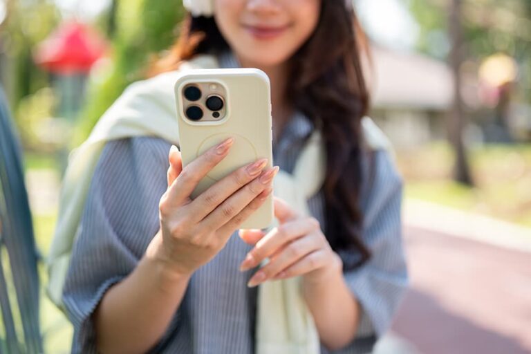 屋外でスマホを操作する女性。タクシーや配車専用車をアプリで選ぶ場面をイメージした写真