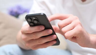 黒いスマートフォンを手に持ち、画面を操作する様子