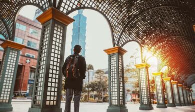 台北101を背景に、アーチ状の屋根の下に立つリュック姿の旅行者