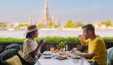 美しいワット・アルンを望むチャオプラヤー川沿いのレストランで、絶景とともにタイでの食事を楽しむカップルの様子を捉えた記事のサムネイル画像